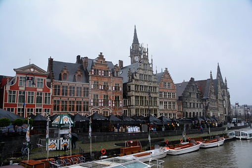 Ghent, Belgium - December 28, 2021: Graslei street with its pier and cafes in the foreground and its medieval houses in the background.