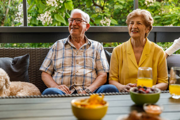istock Smiling senior couple sitting on the sofa and looking at someone off camera 1405484993