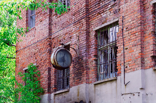 An old round clock hangs on the wall of an abandoned brick building. Halfway through the first.