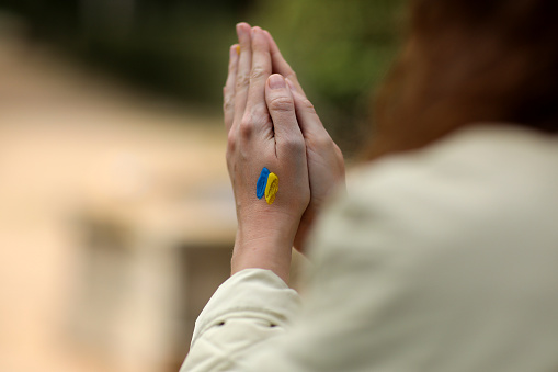Stop War. Peace in Ukraine. woman hands with picture of flag of ukraine, hands folded in prayer. Antiwar support concept. High quality photo