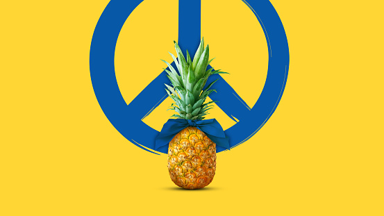 Pineapple with blue bow on yellow background with peace sign. Minimal fruit concept. Creative advertisement idea. Ukraine flag colors. Support Ukraine. Copy space.
