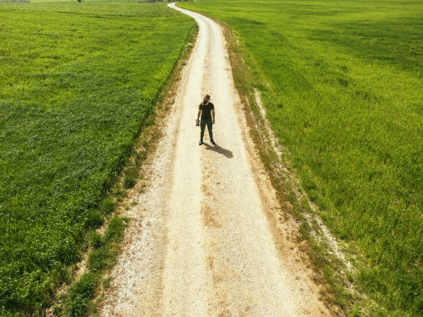 A man in a fedora on the road among the grass