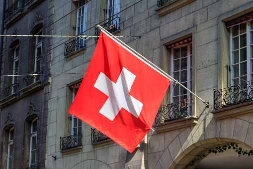 Red Swiss flag hanging from building facade
