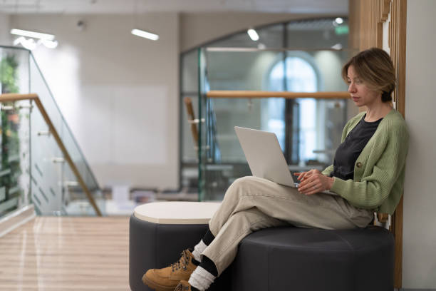 istock Focused pensive middle-aged woman freelancer working on laptop in library 1405494156