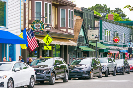 Bar Harbor, Maine, USA- May 26, 2022- A row of cars are parked along Main Street in the heart of Bar Harbor where a variety of shops and restaurants have signs and window displays to entice passing tourists to stop and shop.