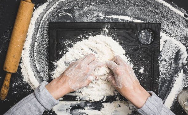 istock two female hands knead the dough from white wheat flour on a black table, top view 1405495555