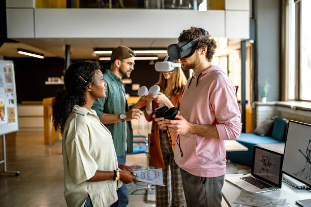 istock Group of university students in the office using VR simulator headsets, having fun 1405498496