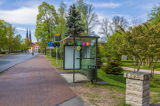Sweden. Uppsala. 05.14.2022 Close up view of buss stop on green trees and cathedral church towers and blue sky on background.