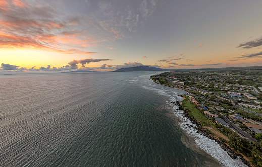 Aerial view of a sunset over the ocean and Hawaiian island coastline.