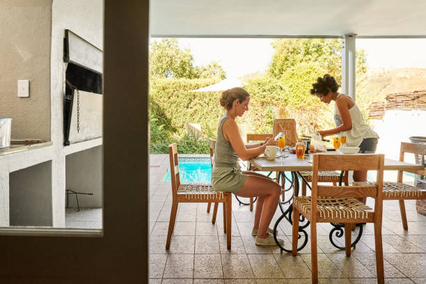 istock Two female friends using phone and making breakfast at breakfast table at home 1405509242