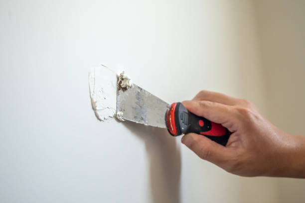 man repairing crack white wall with spatula - plasterer construction site manual worker plaster imagens e fotografias de stock