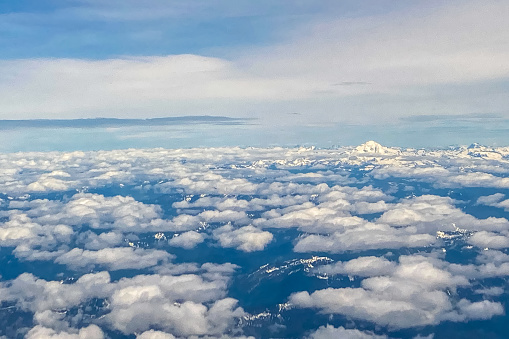 Aerial view of cloud layers and a snow-capped peak over the Cascade Mountains in the northwestern United States.