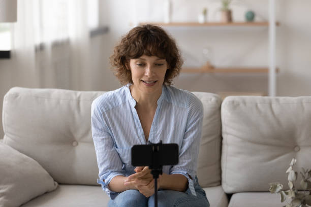 agréable jeune femme séduisante enregistrant une vidéo sur téléphone portable. - working smiling equipment car photos et images de collection