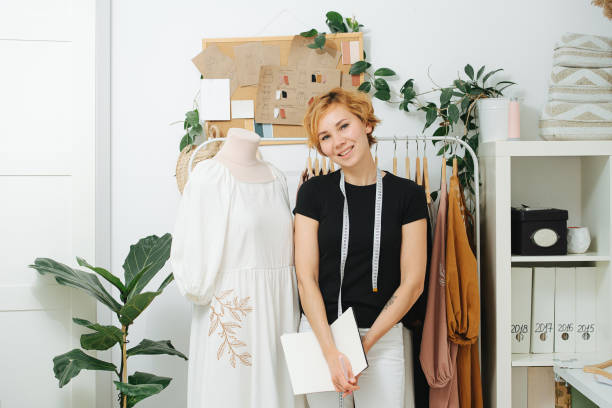 istock Smiling young seamstress in front of a rack next to a mannequin 1405516955