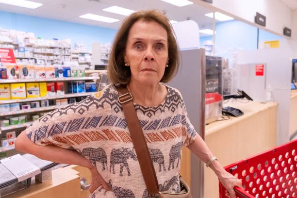 Serious Senior woman scared of prices because inflation looking at the camera while shopping for prescription drugs stock photo
