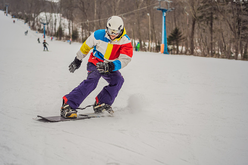 Young man jumping with a snowboard in the mountains.