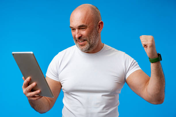 istock Handsome middle age man with digital tablet against blue background 1405519253