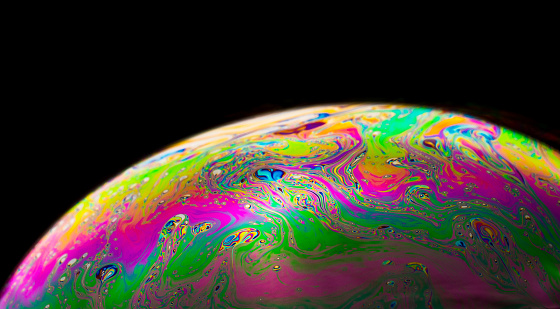 An extreme close up of a single soap bubble showing amazing colorful patterns on the surface.