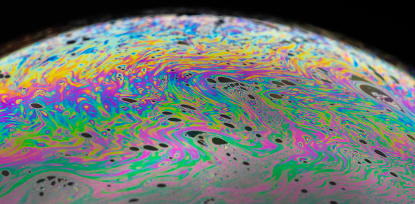 An extreme close up of a single soap bubble showing amazing colorful patterns on the surface.