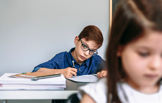 Teen writing in his notebook at school. Selective focus on boy in background