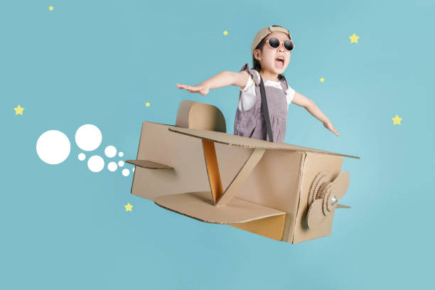 Asian little child girl playing with cardboard toy airplane handicraft isolated on blue long banner with copy space for your text, Creative with family and dreaming of flying concept Asian little child girl playing with cardboard toy airplane handicraft isolated on blue long banner with copy space for your text, Creative with family and dreaming of flying concept science and technology kids stock pictures, royalty-free photos & images