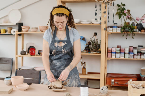 istock Young woman in workwear tying wrapped and packed earthenware item with thread 1405520276