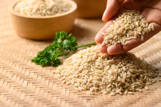 tajski brązowy ryż z ręką, ryż organiczny - brown rice rice heap brown zdjęcia i obrazy z banku zdjęć