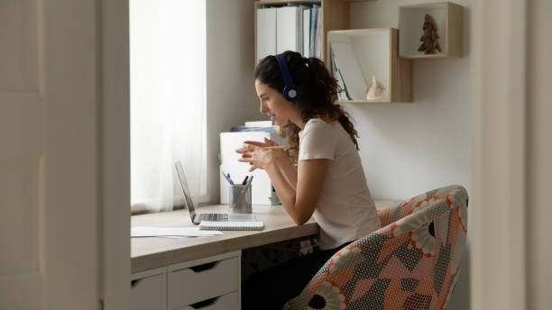 Woman sit at desk using laptop participates in video call Woman sit at desk use laptop participates in video call. Businesswoman in headphones looks at pc screen talk to colleague client remotely, online counseling, distance consultation by videocall concept financial advisor virtual stock pictures, royalty-free photos & images