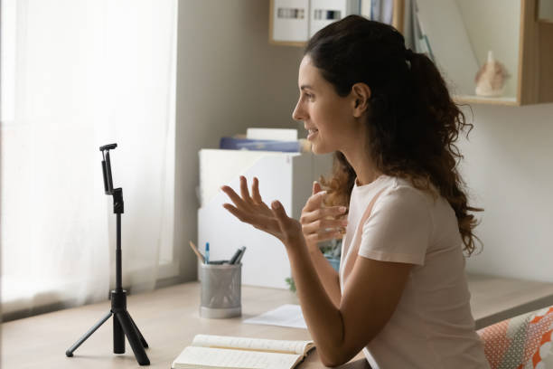 istock Woman sit at desk looking at smartphone camera record videovlog 1405521760