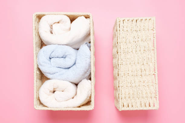 istock Folded towels in wicker boxes close-up top view on in pink background, space organization concept. 1405521864