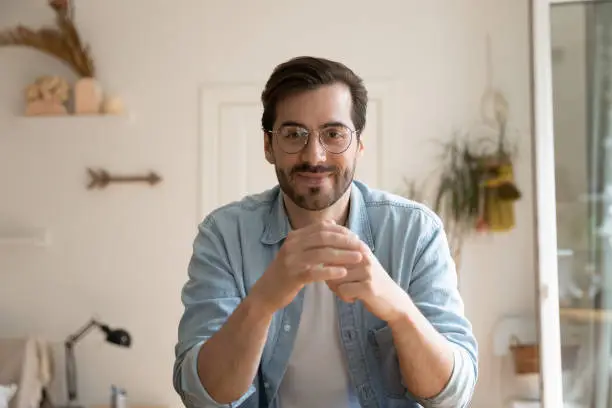 Photo of Man sitting indoor looks at camera participate in live videoconference