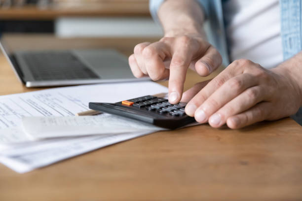 istock Man costs personal incomes and expenses using calculator close up 1405522720