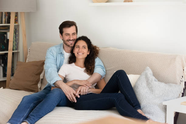 istock Couple hugging resting at home smiling daydreaming looking into distance 1405522754