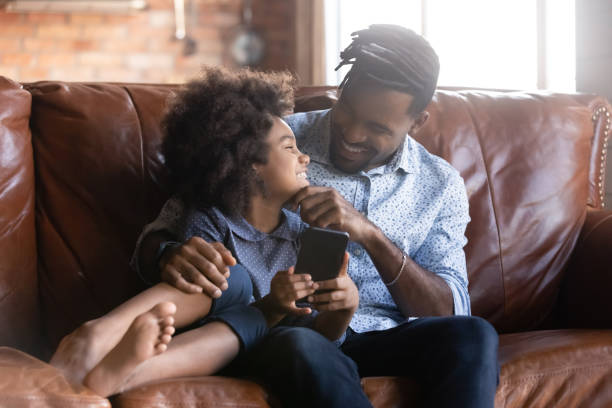 istock Happy little African girl using phone with dad. 1405522793