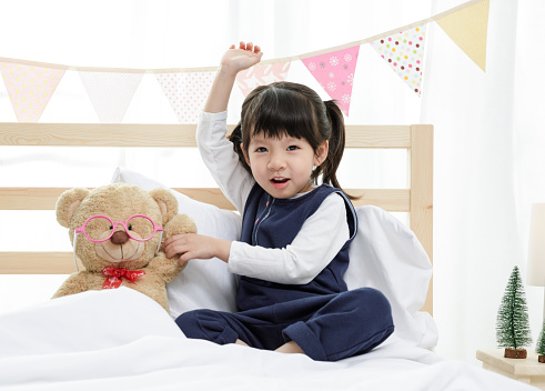 Happy asian child little girl with her teddy bear, family concept at home