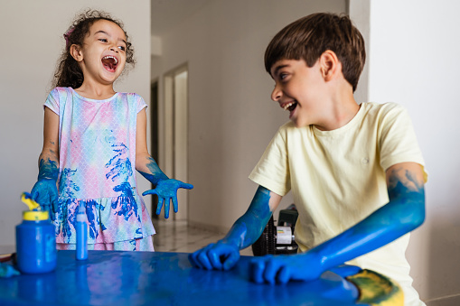 Siblings having fun putting paint on their clothes