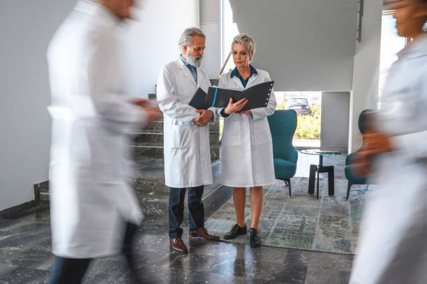 istock Two Older Doctors Check Test Results in Busy Office 1405531349