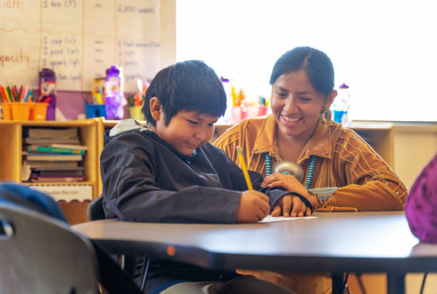 Helpful teacher encouraging one of her students Indigenous Navajo Helpful teacher encouraging one of her students high school student classroom education student stock pictures, royalty-free photos & images