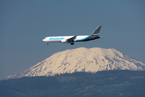 Portland, Oregon, USA - June 24, 2022: An Amazon Prime Air Boeing 767, operated by Atlas Airlines, comes in for landing at Portland International Airport with a snow covered Mount St Helens in the background.