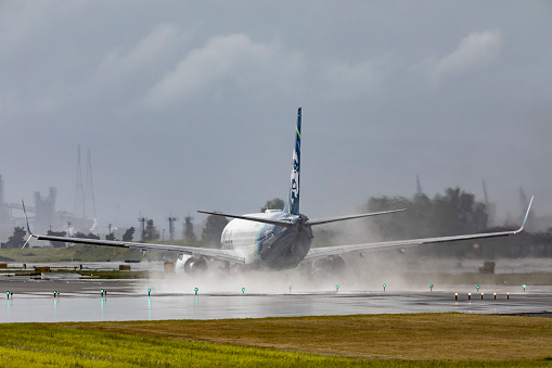 Portland, Oregon, USA - May 6, 2022: An Alaska Airlines 737 begins the takeoff roll on a wet runway at Portland International Airport.