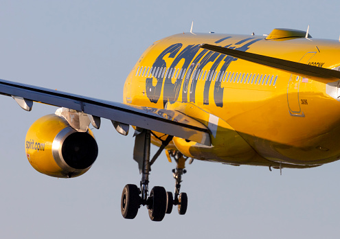 Portland, Oregon, USA - March 19th 2022: A Spirit Airlines A320 landing at Portland International Airport into a setting sun.
