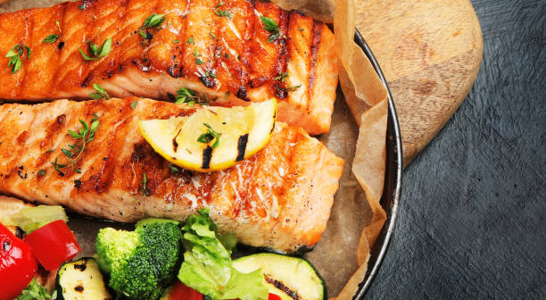 istock Salmon steak with vegetables on dark background. 1405534889