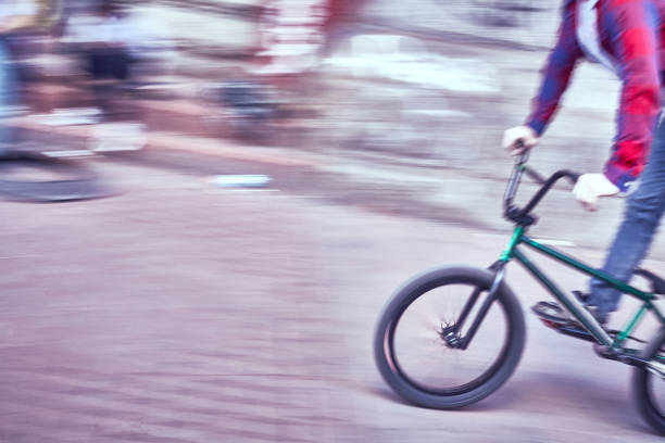 Bmx rider performing an acrobatic backflip stunt in a skatepark under a cloudy sky