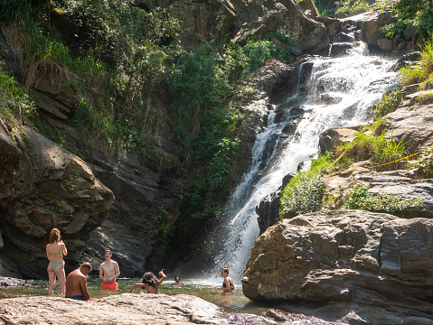 Ella, Sri Lanka - March 9, 2022: Beautiful view of the Ravana Ella waterfall, 25 meters high. People relax and bathe in cool water.