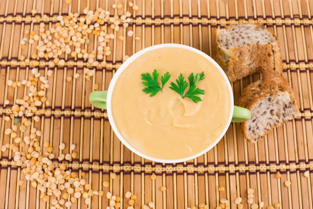 Pea soup in a green bowl with parsley. Whole background. It is located on a striped surface. Close-up.