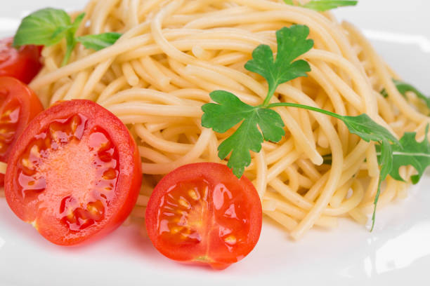 Delicious Italian pasta with tomatoes. Whole background. It is located on a white surface. Close-up.