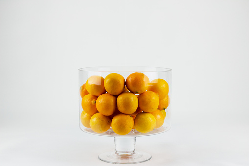 Fresh orange-colored tangerines grouped in a transparent glass fruit bowl. landscape photography