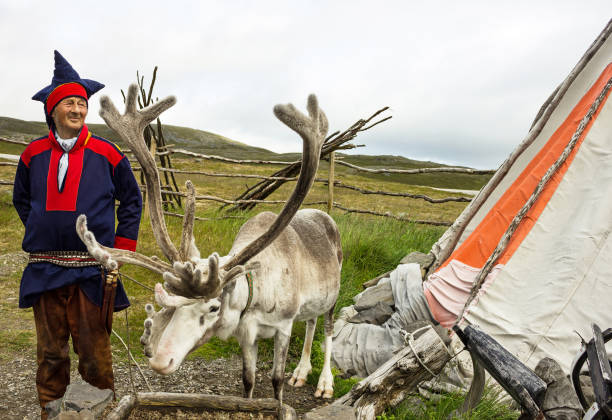 Deer and reindeer breeder dressed in national clothes the Sami in the area of town Honningsvag, Norway. stock photo
