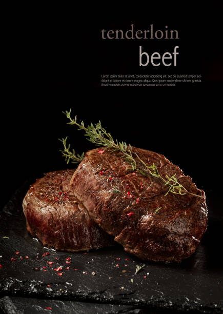 Delicious beef steak with spices and herbs Appetizing juicy tenderloin beef steaks with peppercorns and thyme sprigs on slate board against black background with lettering steak stock pictures, royalty-free photos & images