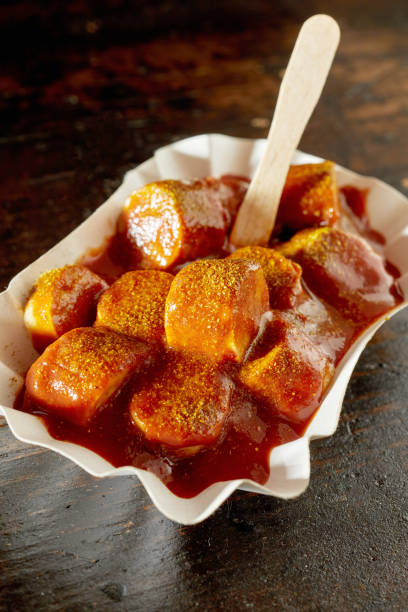 currywurst con ketchup y palo desechable en recipiente de cartón - currywurst fotografías e imágenes de stock